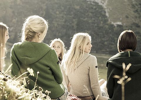 Frauen von hinten am Wasser sitzend