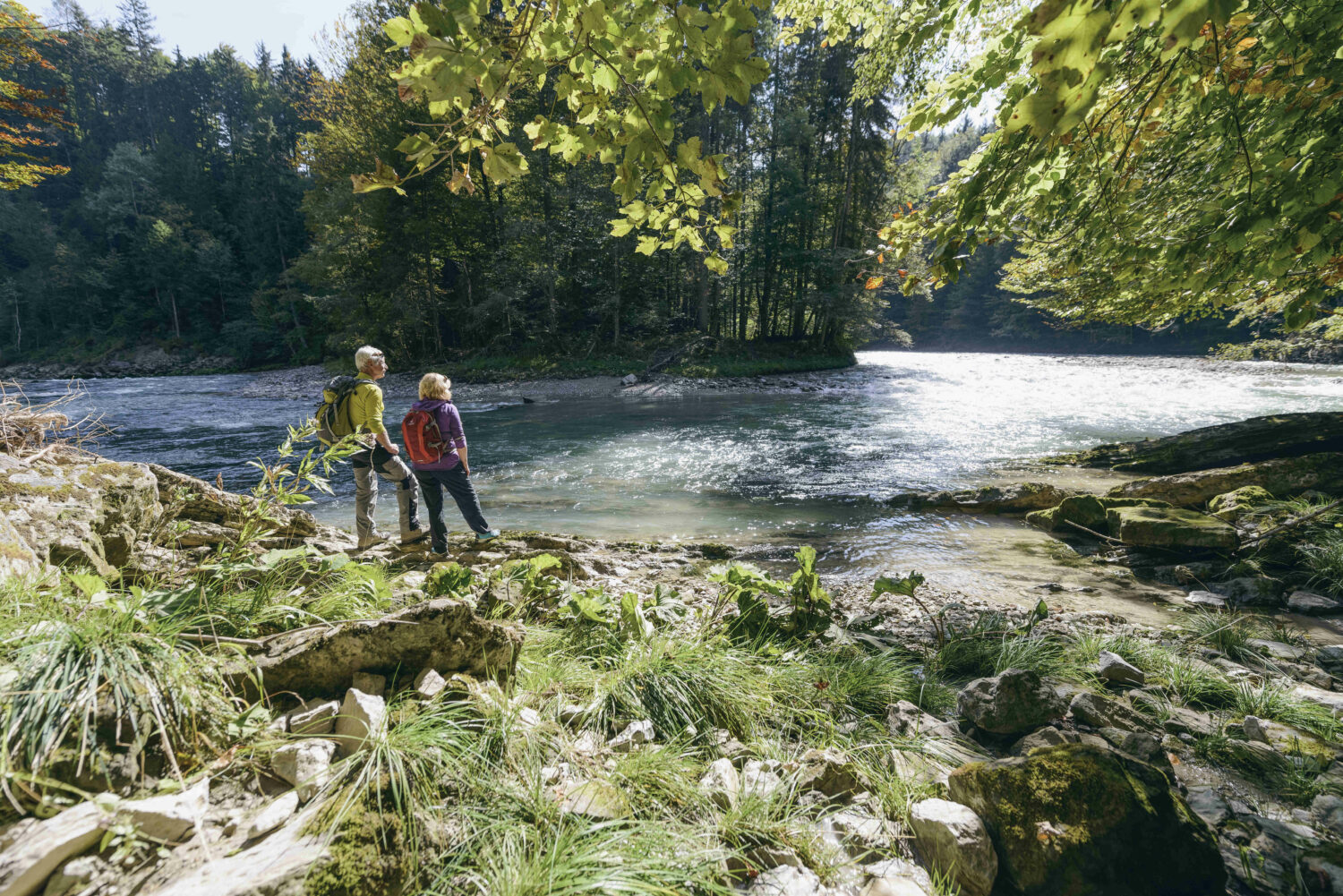 Zwei Wanderer rasten am Fluss.